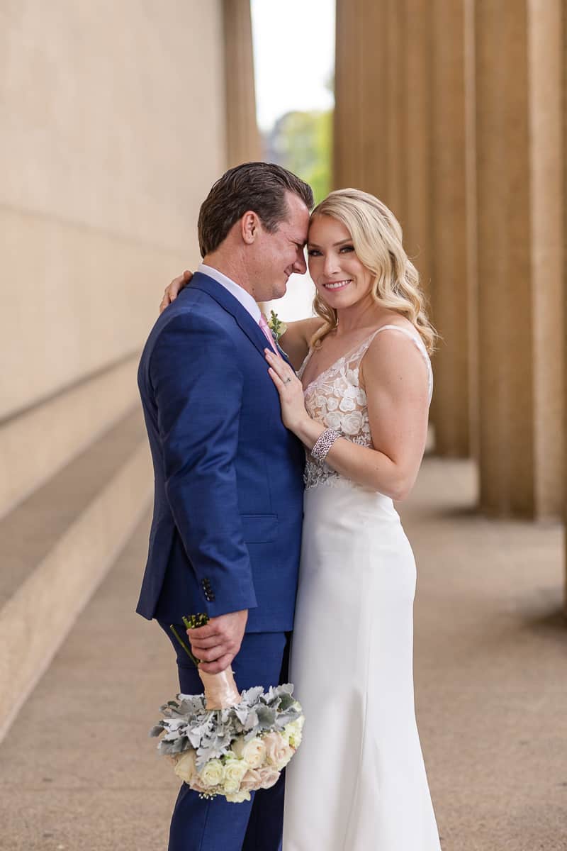 bride and groom pose among architectural columns